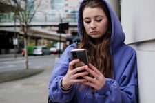 Jugendliches Mädchen nutzt ihr Handy auf der Straße, um mit einem KI-Chatbot zu sprechen