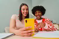 2 jeunes adultes souriantes apprenant une langue avec une application alternative a Babbel