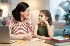 A tutor sitting next to her student during an at-home lesson