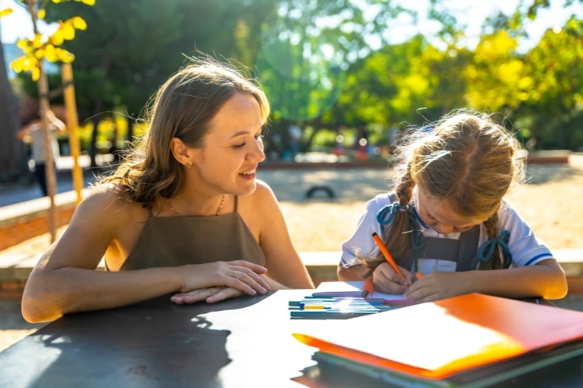 A mother with her daughter reviewing school books outdoors
