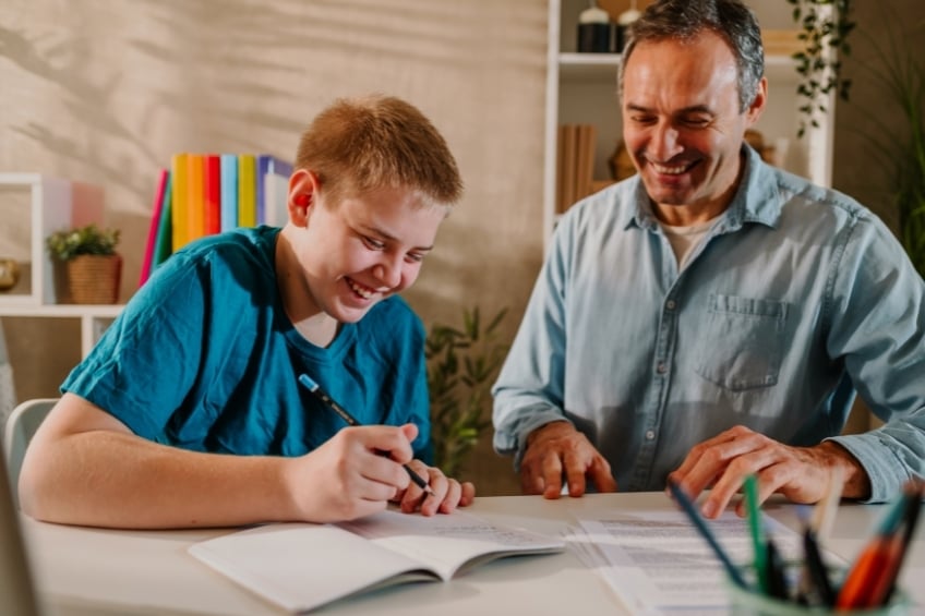 A private tutor and their student during a lesson laughing together