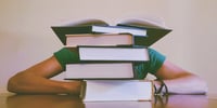 studente dietro montagna di libri