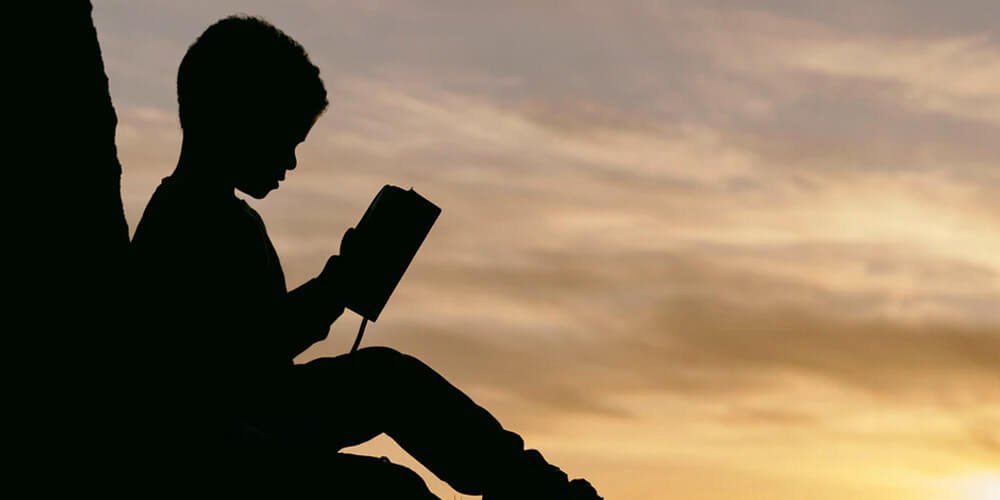 Come studiare in estate ragazzo legge al tramonto
