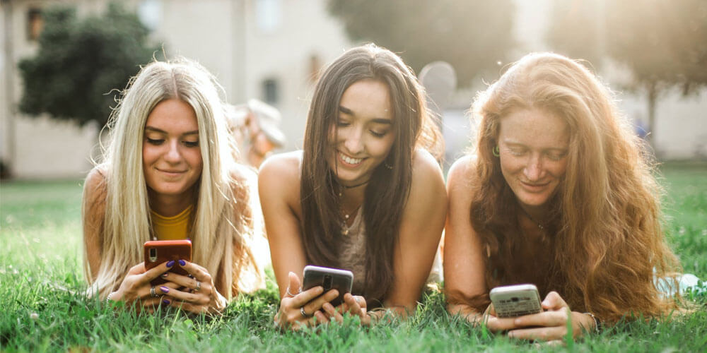 Cyberbullismo su Facebook tre ragazze al telefono