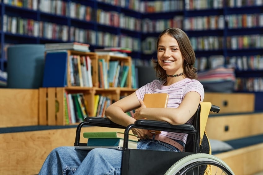 Eleve en fauteuil roulant trouvant des livres pour preparer son brevet en candidat libre