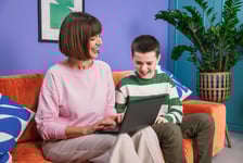Mutter und Sohn schauen auf den Laptop und lesen GoStudents Bericht zur Zukunft der Bildung in 2024