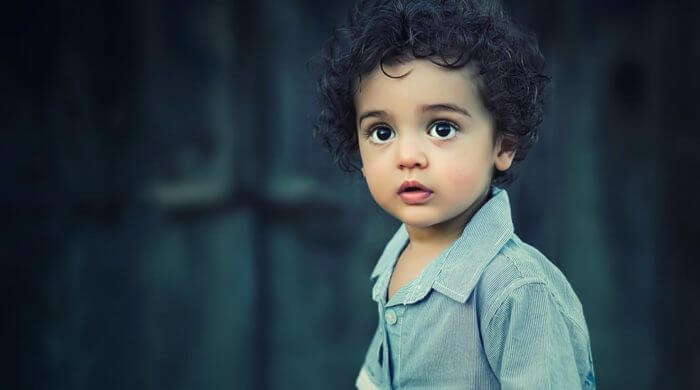 child with curly hair looking at the camera