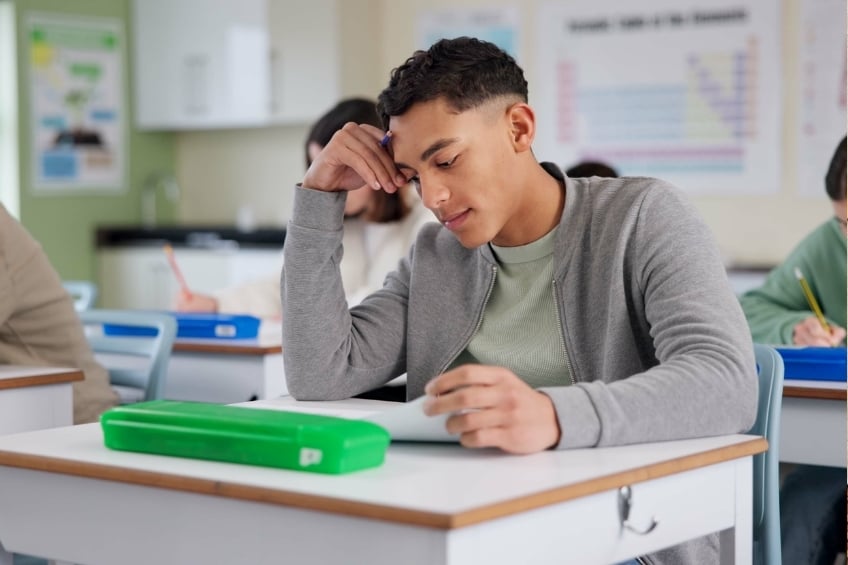 adolescent demotive et en decrochage scolaire assis devant son evaluation en cours
