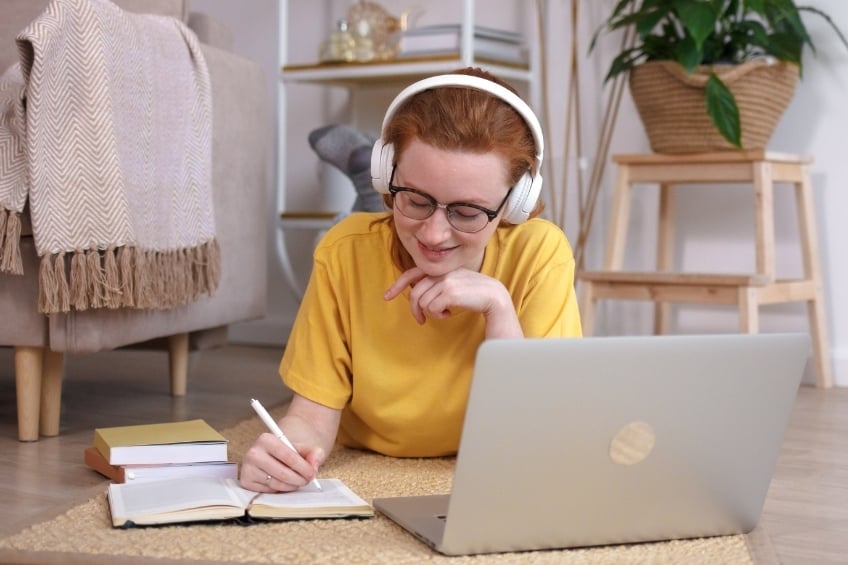 GoStudent vs Groupe Reussite - une eleve suivant des cours particuliers en ligne allongee par terre