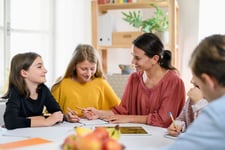 Groupe de eleves en cours particuliers a domicile avec une professeure dans un salon