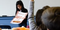 estudiante en clase de español levantando la mano