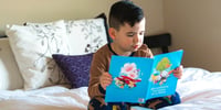 niño leyendo cuento en su cama