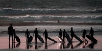 Adolescent surfant au coucher de soleil