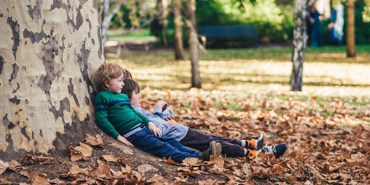Enfants adossés à un arbre en forêt