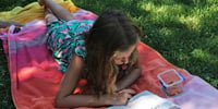 fine anno scolastico ragazza legge sul prato
