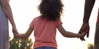 girl holding hands with parents