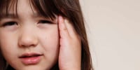 child with hand over ears