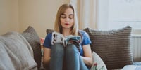 Girl reading book on sofa