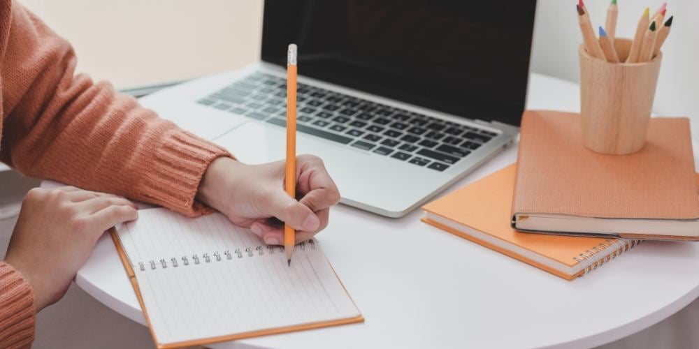 estudiante-escribiendo-ordenador-libreta