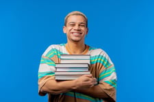 Jeune adulte tenant une pile de livres dans ses bras pour preparer le TOEIC