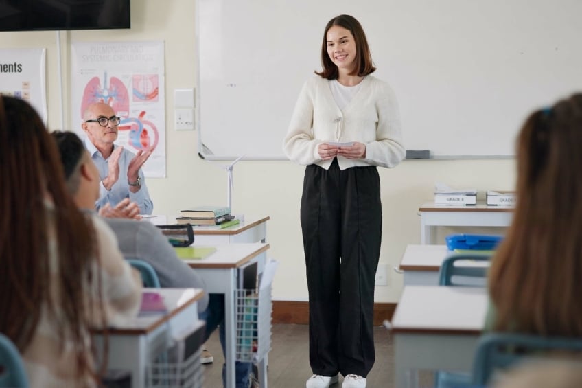 Lyceenne debout devant sa classe pratiquant pour sa presentation du grand oral du bac - GoStudent