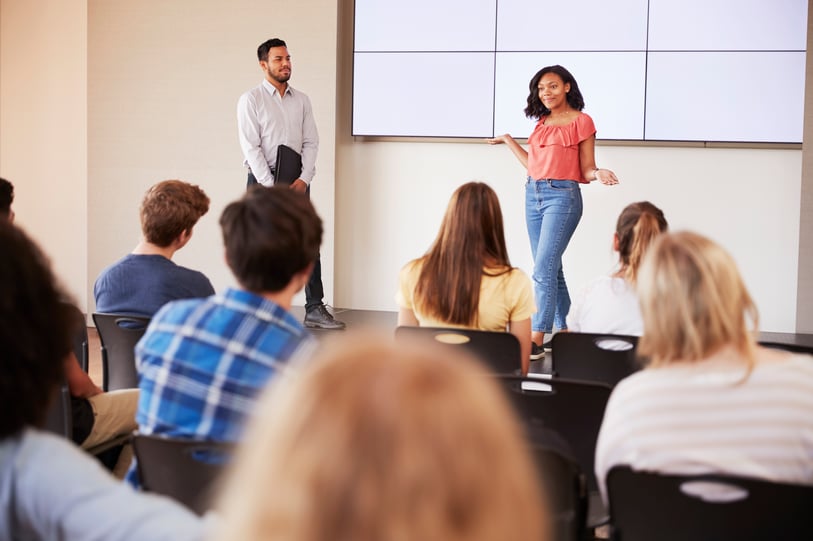 Schülerin präsentiert mündliche Abiturprüfung vor Lehrerin und Mitschülern