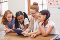 teacher showing students work on a tablet