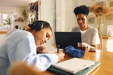 Teenage girl studying and reviewing textbooks next to her mom before school starts