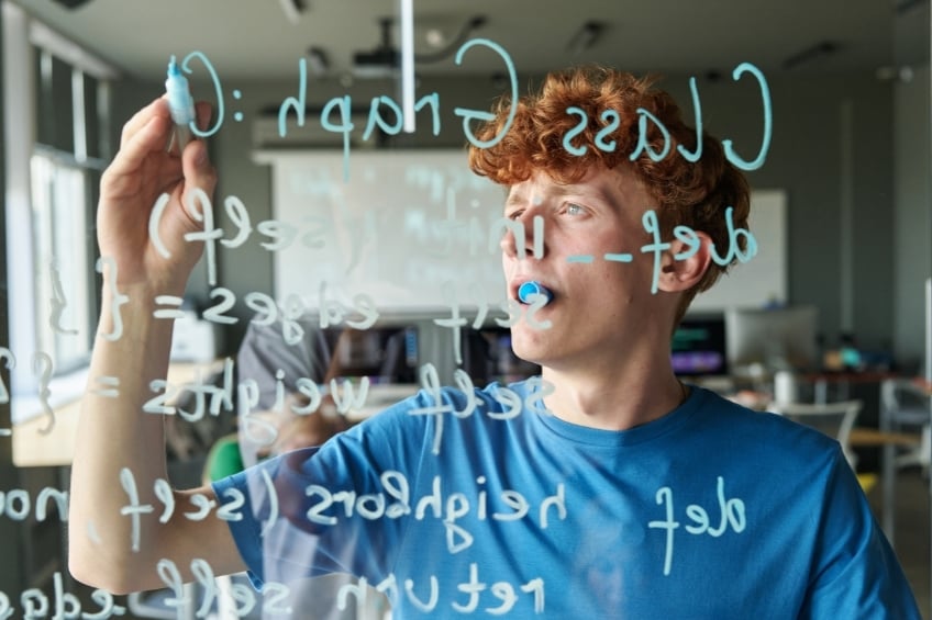 Un lyceen ecrivant un raisonement mathematique sur un tableau
