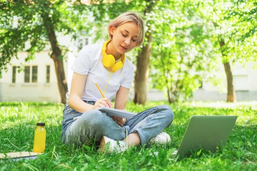 Une lycenne se prepare et revise pour passer le bac en candidat libre dans un parc ensoleille