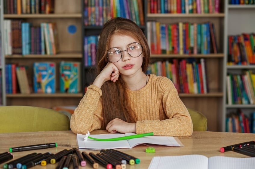 Young girl distracted struggling to read to prevent summer slide