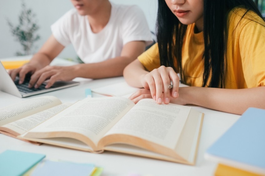englisch-abitur-muendlich-vorbereitung-schueler-liest-notizen-lachend