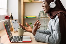 etudiante-souriante-avec-casque-audio-suit-un-cours-en-ligne-sur-son-ordinateur-portable