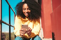 femme-souriante-teste-alternatives-a-duolingo-smartphone-exterieur