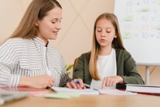 tutor-explaining-homework-to-student-pointing-notebook-page