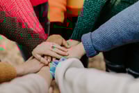 women putting hands together in a circle