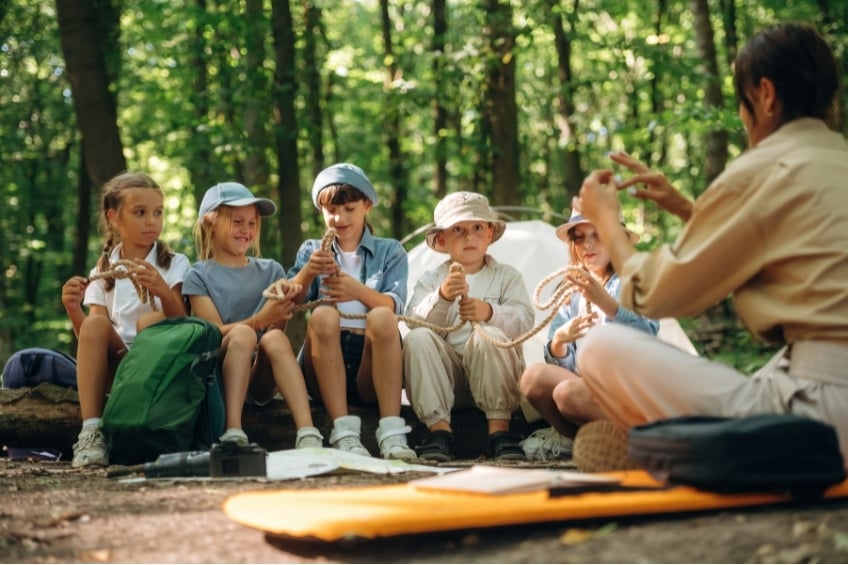 outdoor camp counselor teaching children in the woods