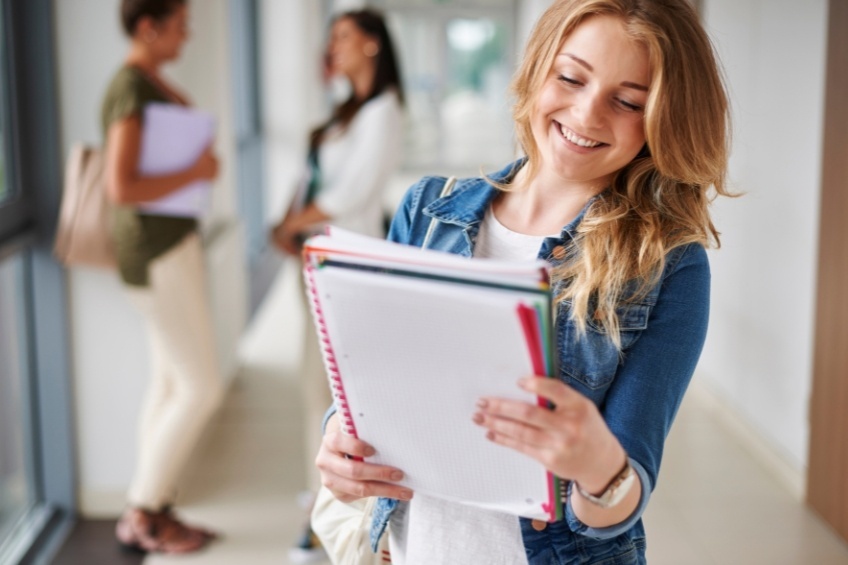 smiling-student-carries-a-level-revision-notes-school-corridor