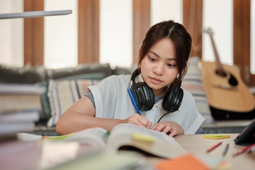 smiling-student-writing-revision-notes-for-her-gcses