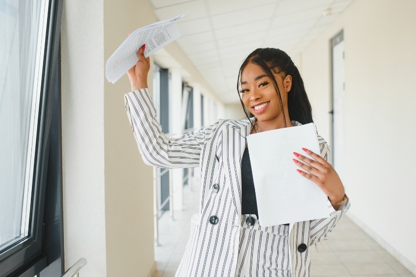 student-celebrating-gcses-results-raising-exam-papers-smiling