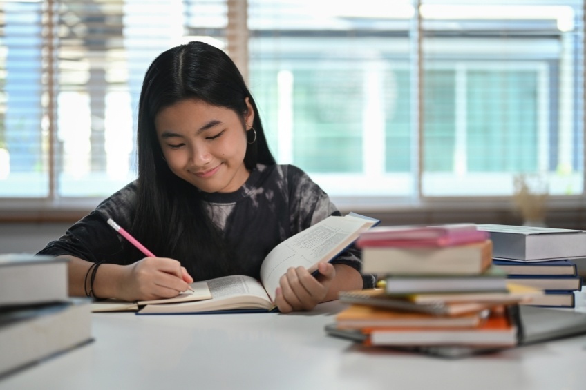 student-holding-a-stack-of-textbooks-used-to-prepare-for-gcses