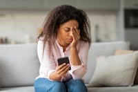 A young woman appears stressed while looking at a mobile phone