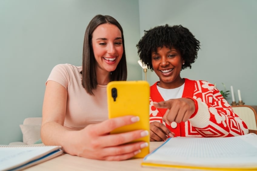 2 jeunes adultes souriantes apprenant une langue avec une application alternative a Babbel