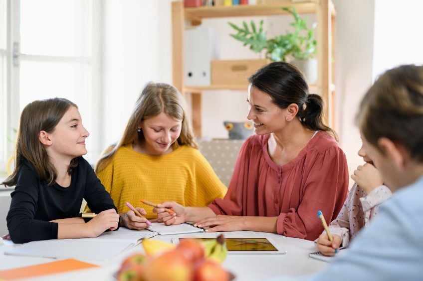 Groupe de eleves en cours particuliers a domicile avec une professeure dans un salon