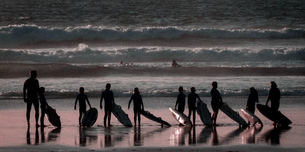 Adolescent surfant au coucher de soleil
